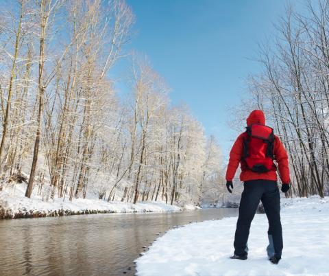 Person hiking in winter near stream