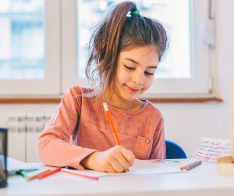 Girl with pony tail writing at a table