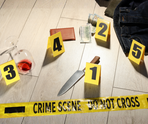 Crime scene objects including clothes, money, knife, spilled glass and crime scene tape
