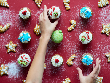 Hands reaching for holiday cupcakes