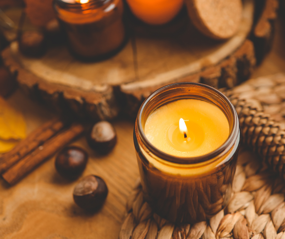 Candles in Glass Jars with chestnuts and wood and cinnamon sticks on a table
